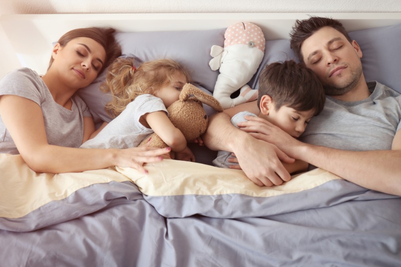 Two adults and two children resting together in bed